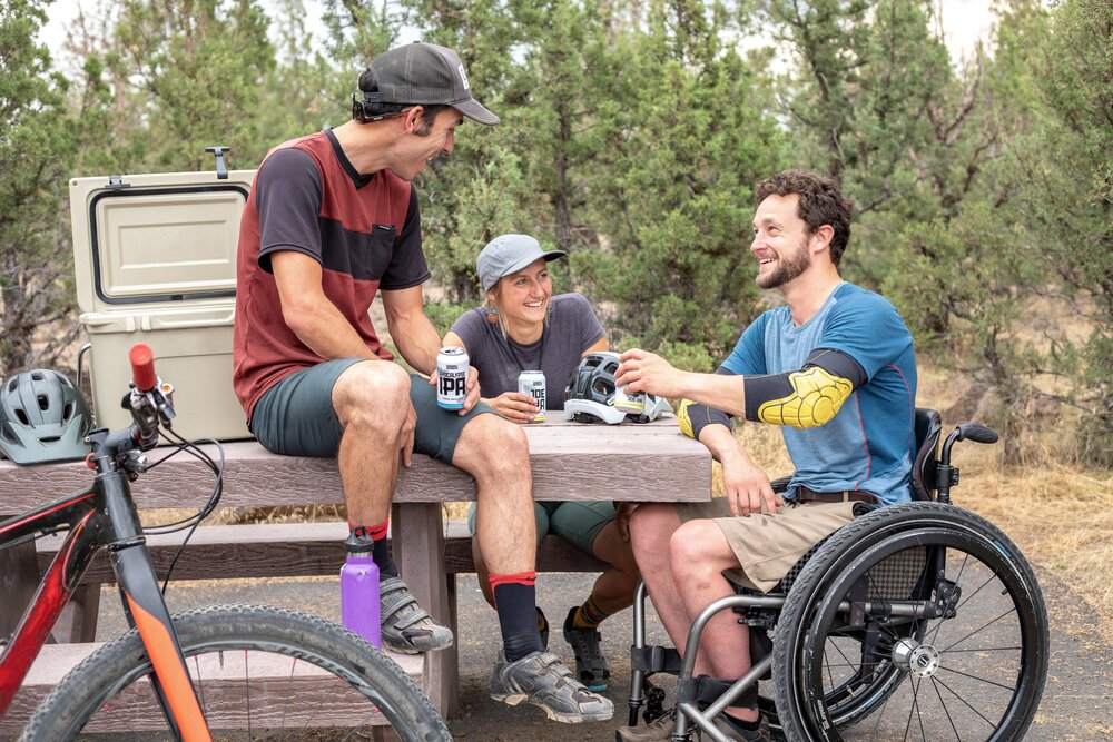 [Translate to Englisch:] Mann im Rollstuhl beim Picknick mit Freunden