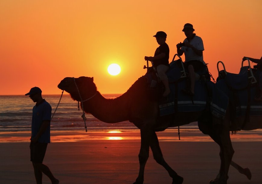 Opa und Enkel auf einem Camel bei Sonnenuntergang 