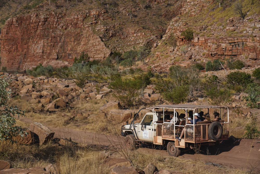 Ein Jeep mit Gästen fährt durch deas Outback