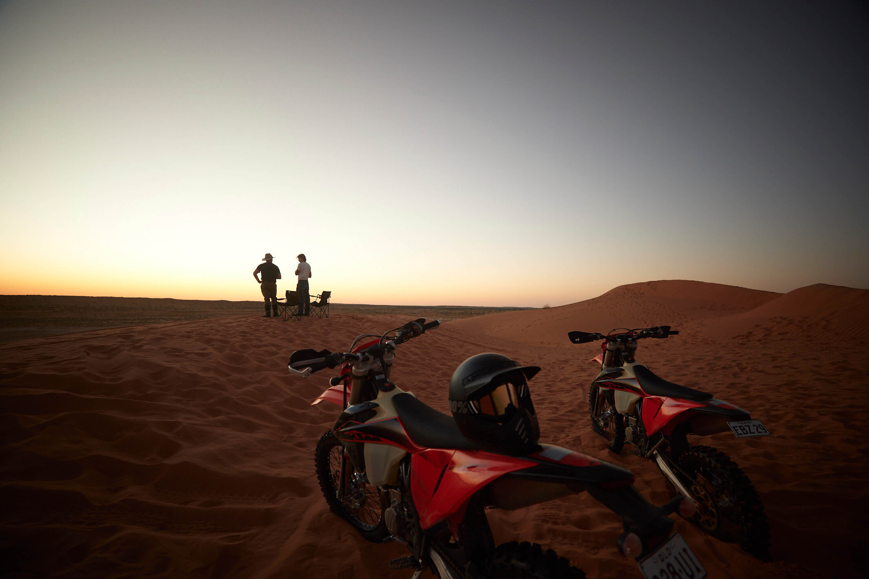 Zwei Männer beobachten den Sonnenuntergang mit ihren zwei Motorrädern