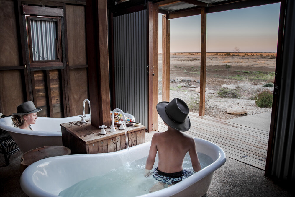 Women In Bathtubs Side by Side With Sunset View of Safari, Caravan Park Julia Creek, Credit Tourism and Events Queensland.